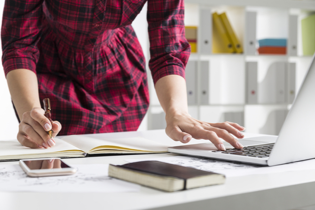 woman with laptop, notepad and phone